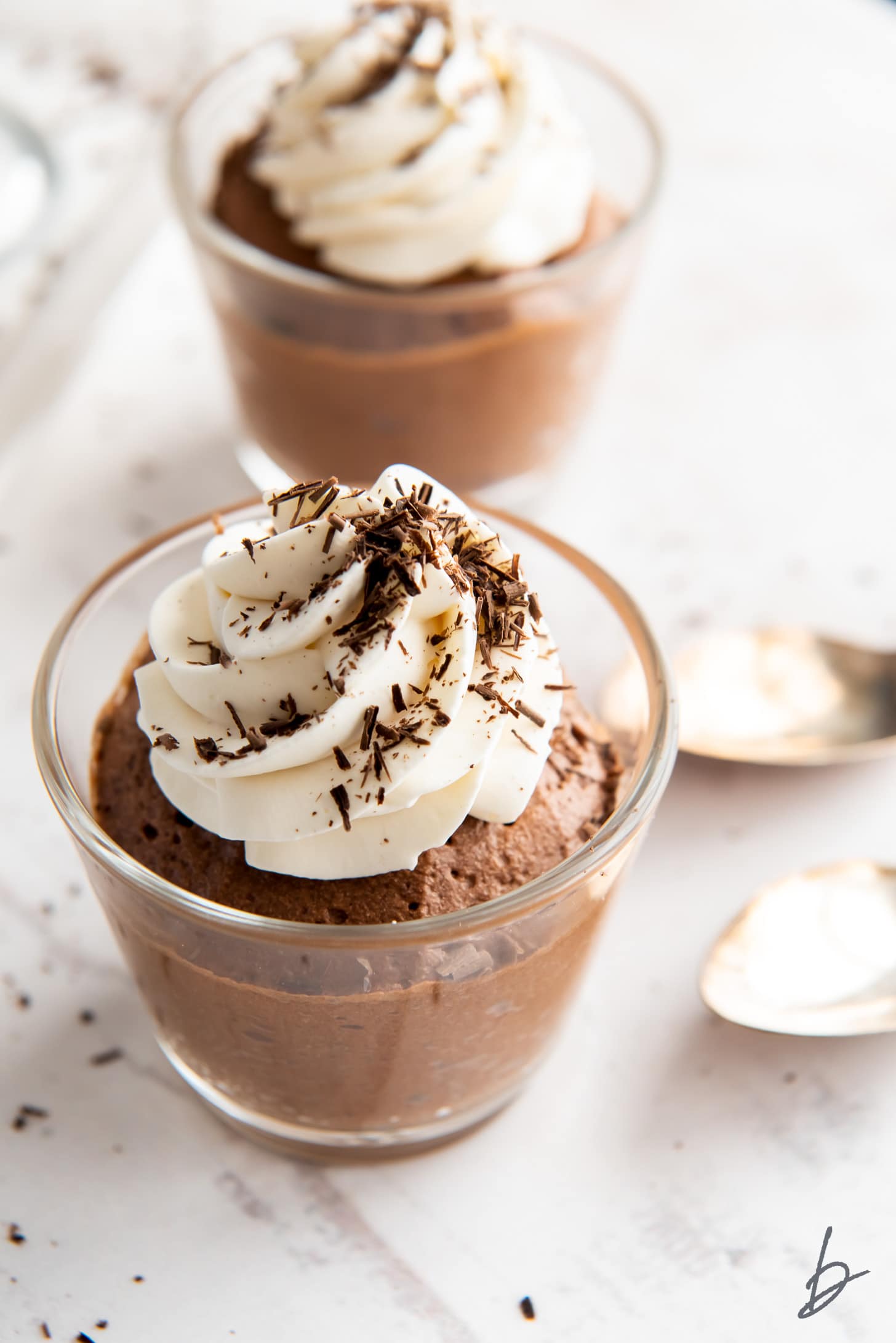 chocolate mousse in a glass jar topped with whipped cream and chocolate shavings