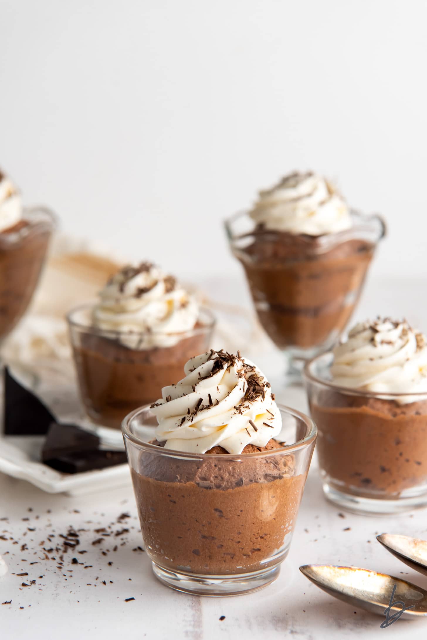 four glass jars topped with whipped cream and chocolate shavings