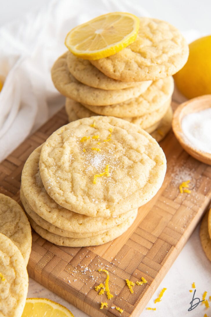 lemon sugar cookies in stacks on brown cutting board