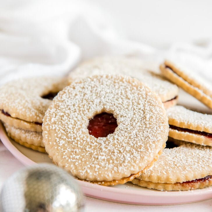 linzer cookie dusted with confectioners sugar and hole in center to show raspberry jam