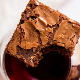 red wine brownie with a bite sitting on top of glass of red wine