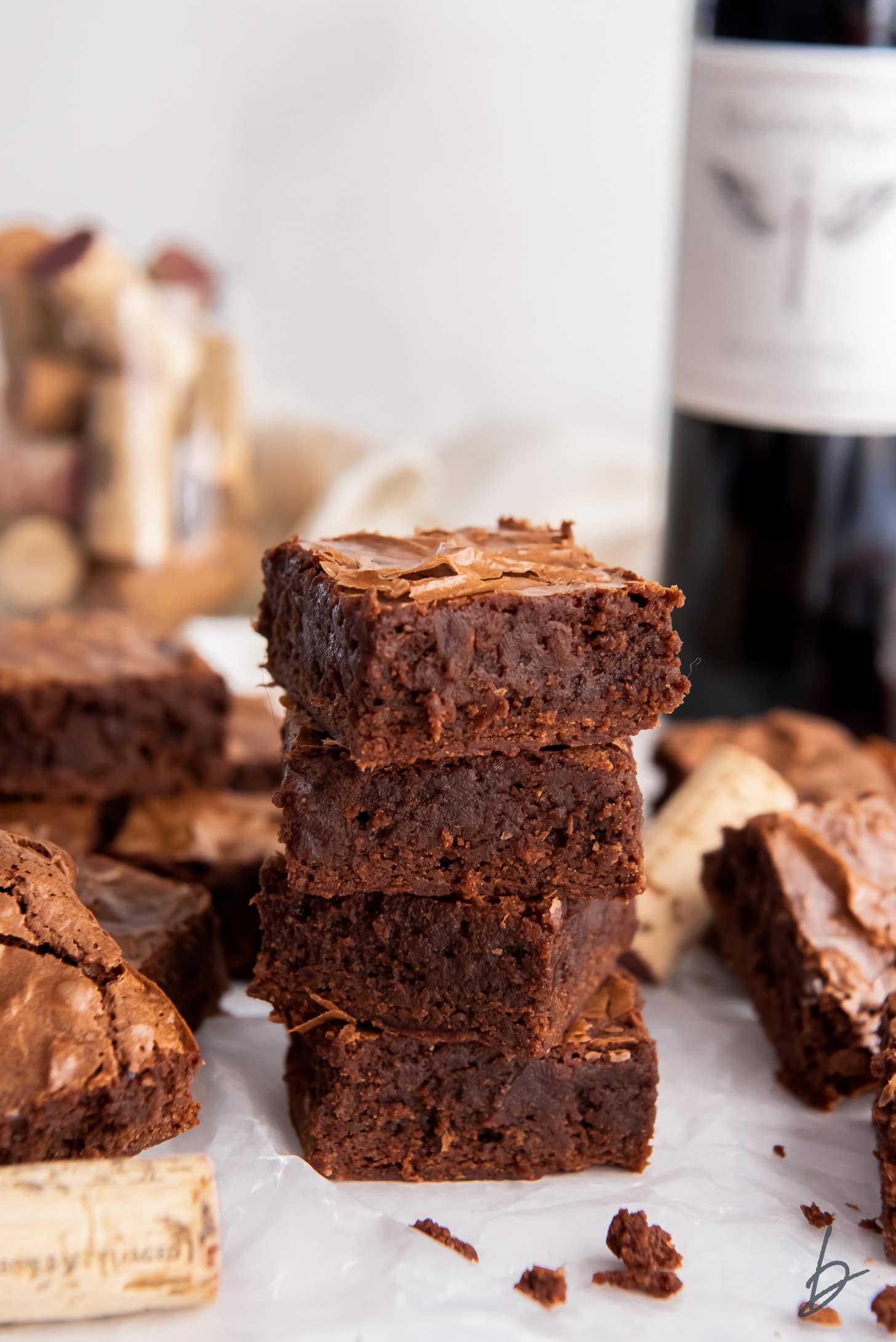 stack of four red wine brownies next to wine cork and bottle of red wine.