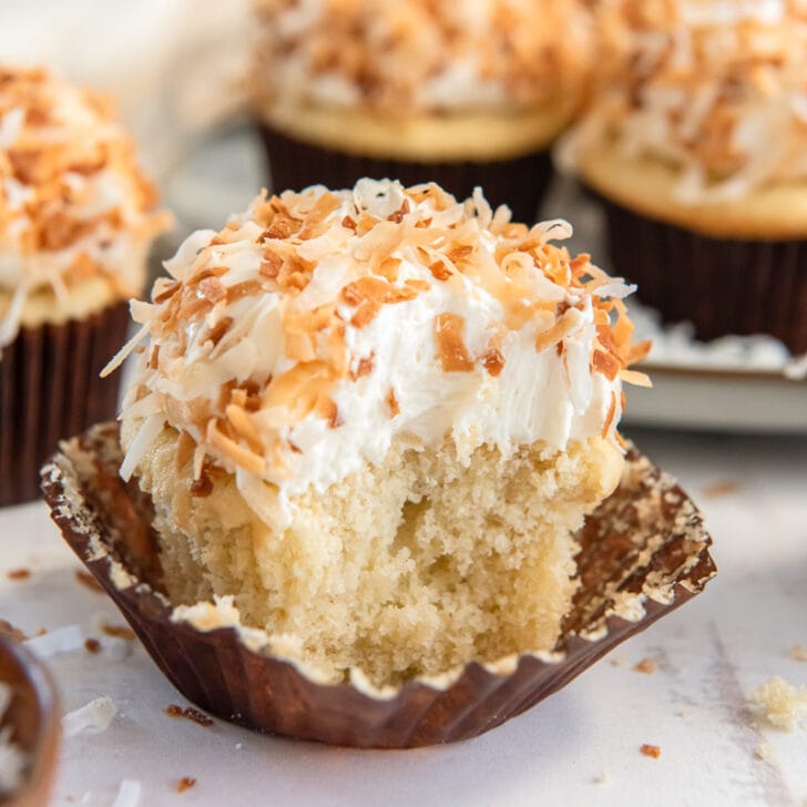 coconut cupcake with a bite and toasted coconut on top of frosting