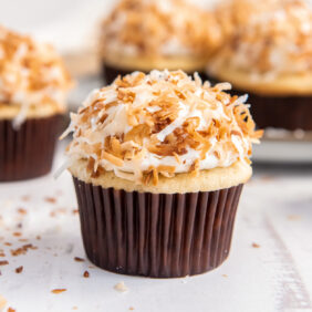 coconut cupcake with brown paper liner and toasted coconut on top