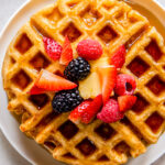 buttermilk waffles topped with maple syrup and fresh berries