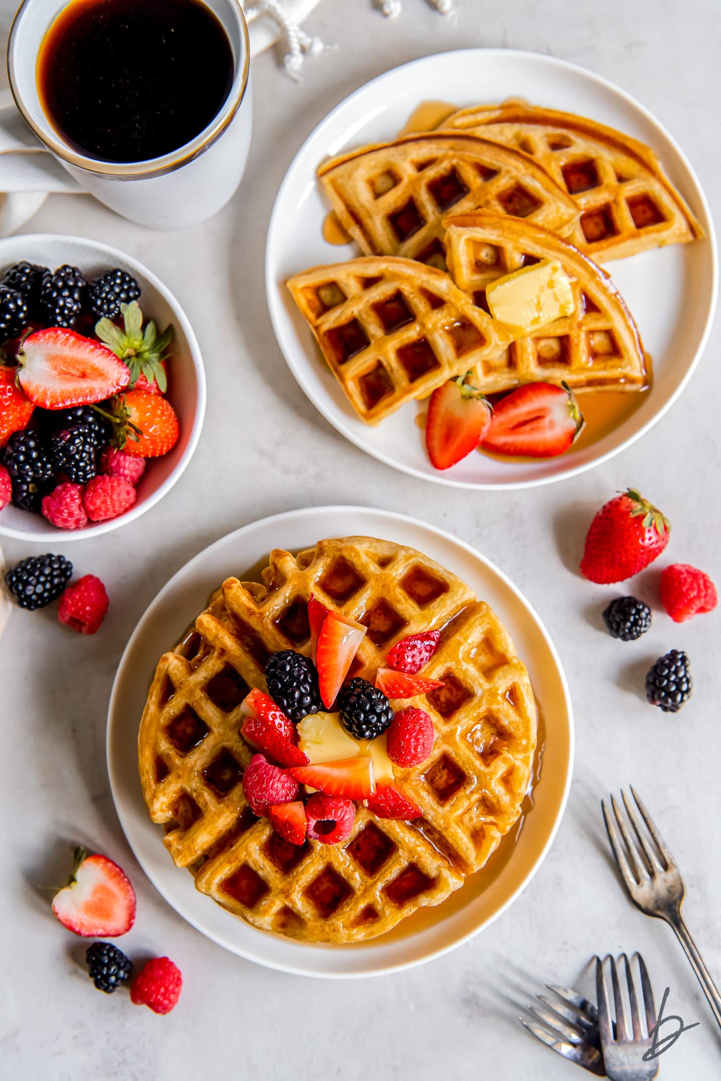 two plates with buttermilk waffles one plate with fresh fruit on waffles the other plate with triangle waffles