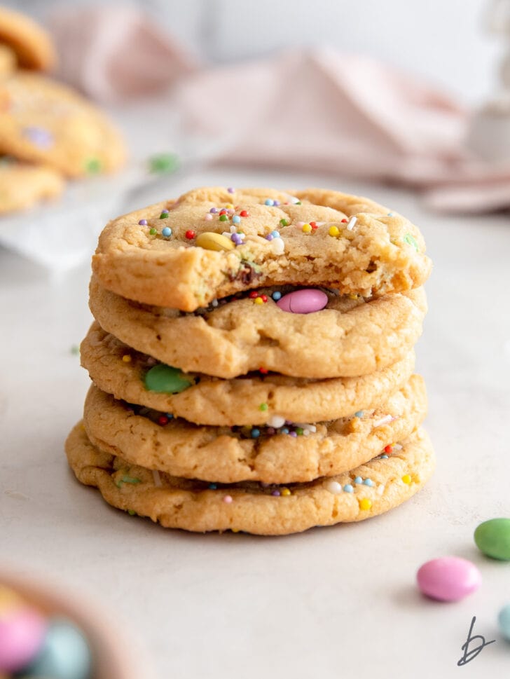 stack of five easter cookies with pastel m&ms and sprinkles and top cookie with a bite