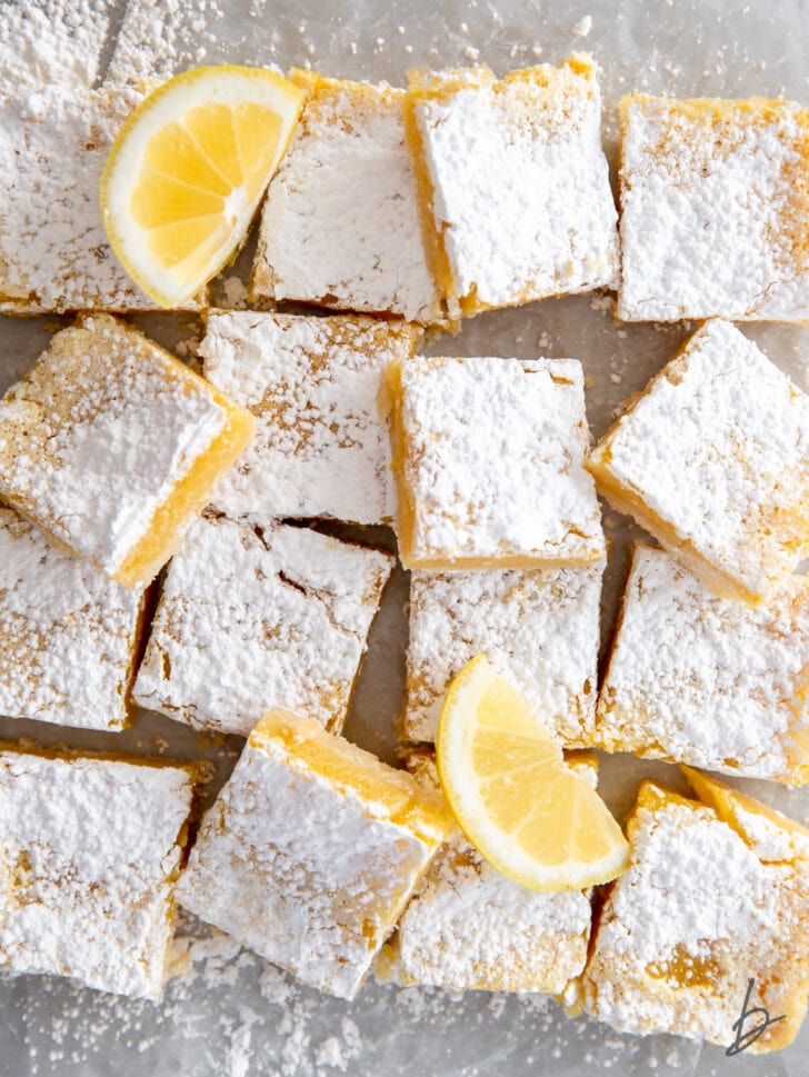 pile of lemon bars with confectioners' sugar and a couple of lemon slices