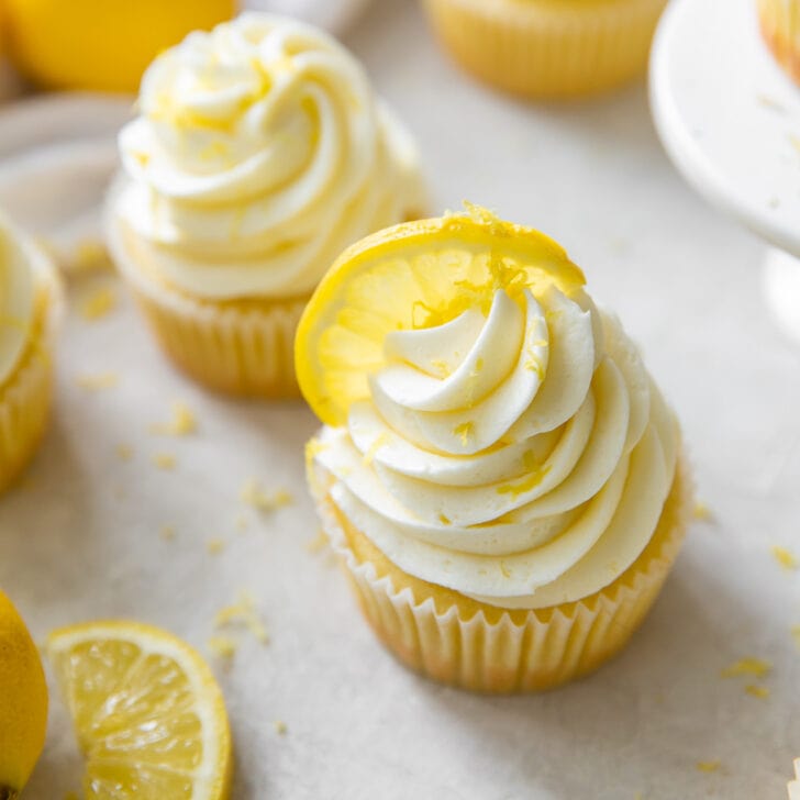 lemon cupcake topped with fluffy lemon buttercream and garnished with lemon slice and zest