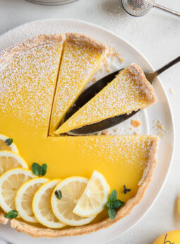 lemon curd tart garnished with lemon slices and two slices cut from tart