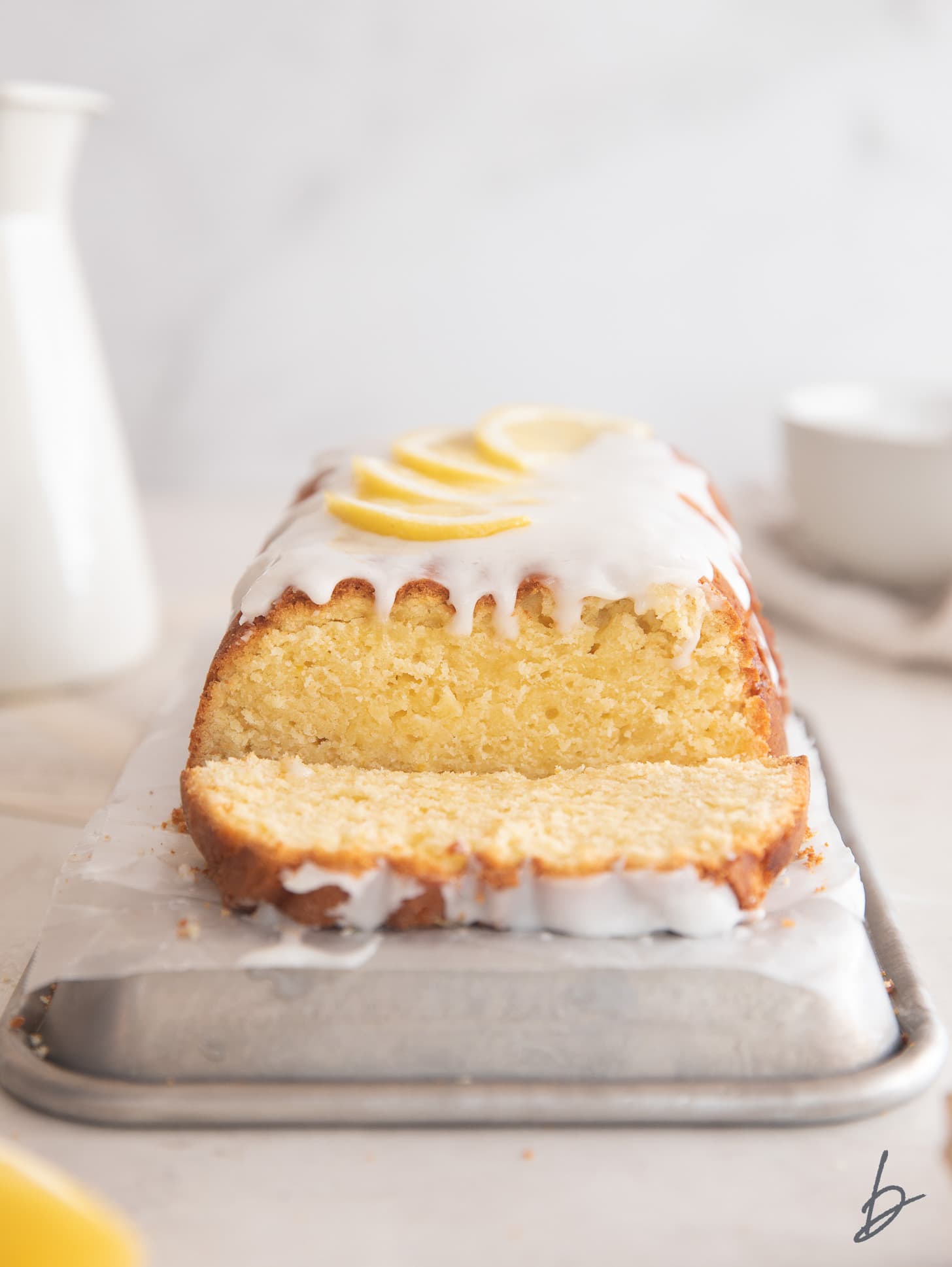 lemon pound cake with icing and slice cut off the end showing inside of loaf