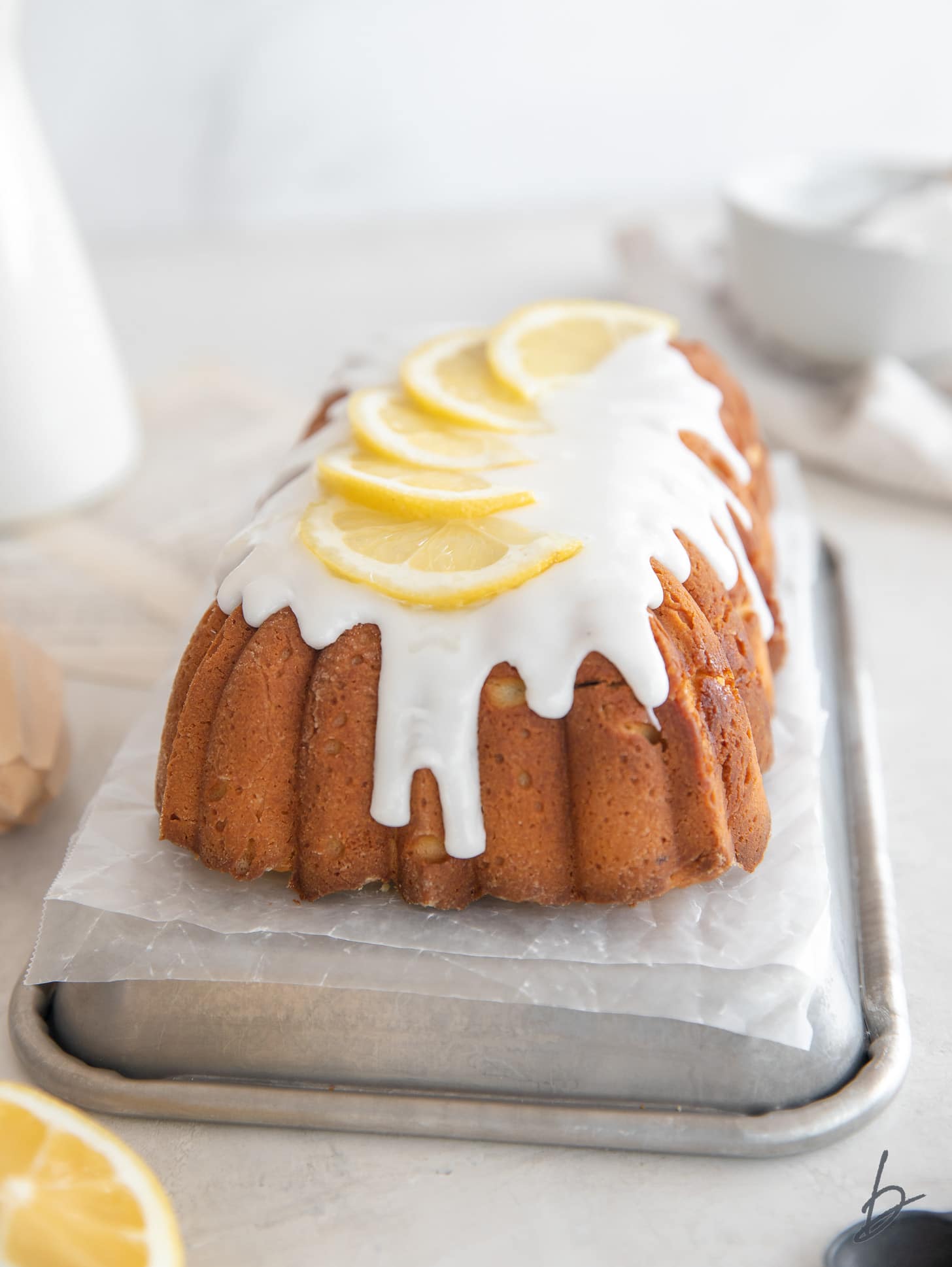 lemon pound cake loaf topped with icing dripping down the front and lemon slices on top