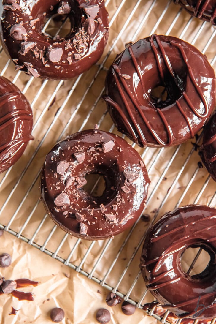 chocolate glazed chocolate donuts on wire cooling rack over parchment paper