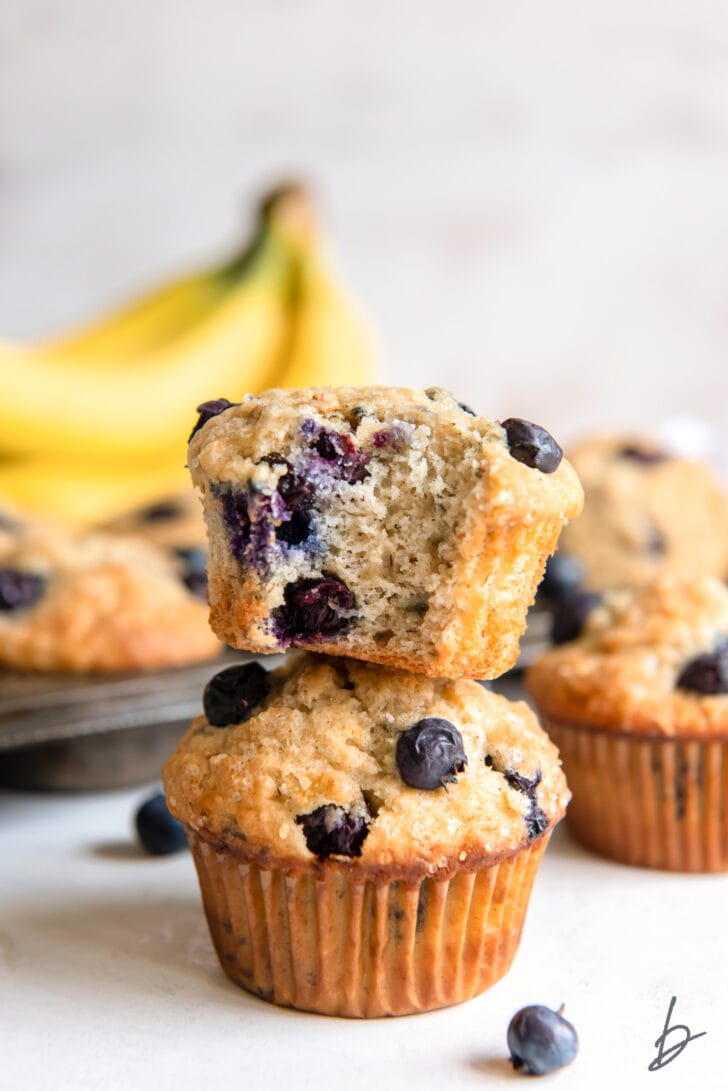 stack of two blueberry banana muffins and top muffin has a bite