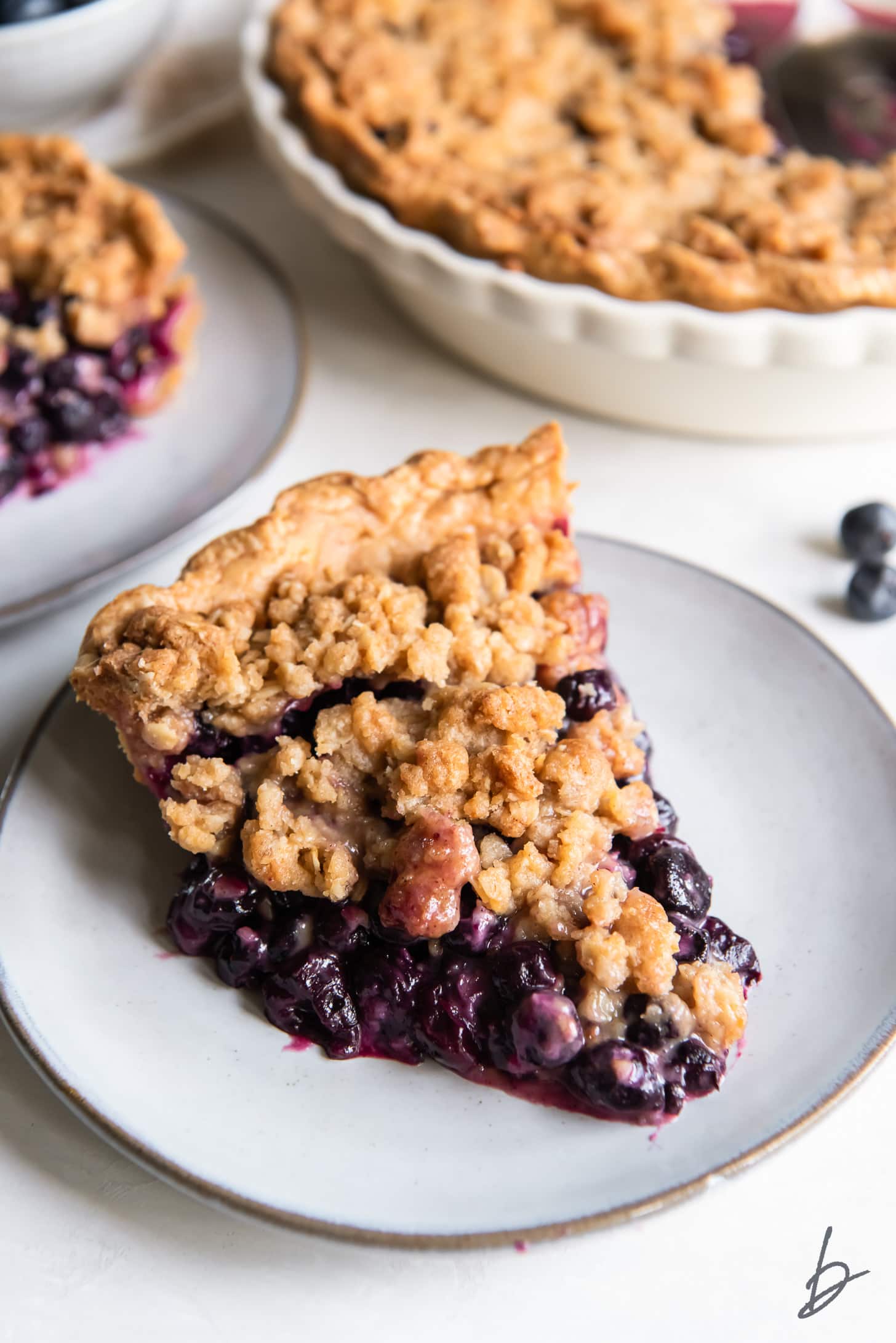 slice of blueberry crumble pie will juicy filling on round grey plate