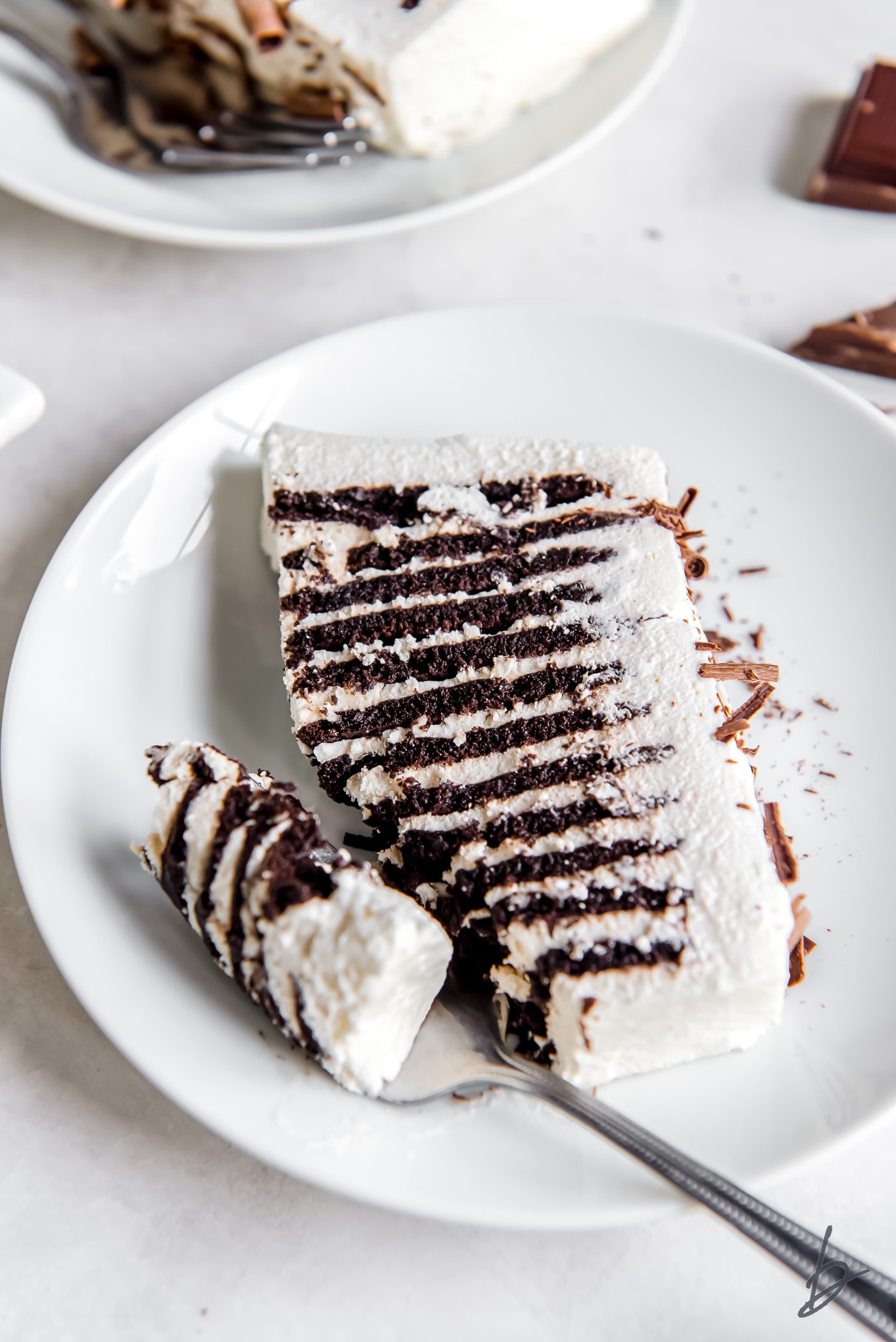 fork taking a bite of chocolate icebox cake on a plate
