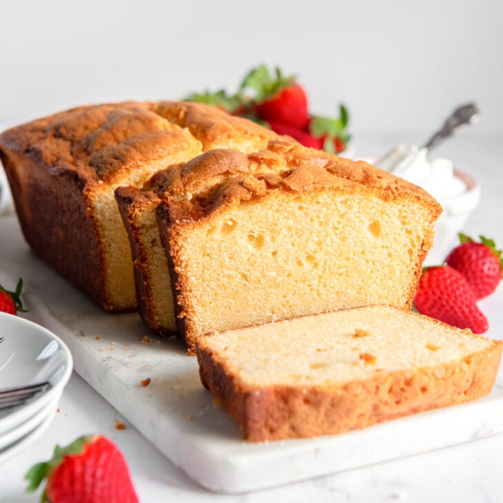 pound cake loaf with slice cut off the end next to strawberries