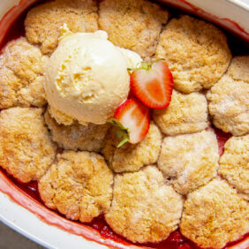 baking dish with strawberry cobbler and scoop of vanilla ice cream