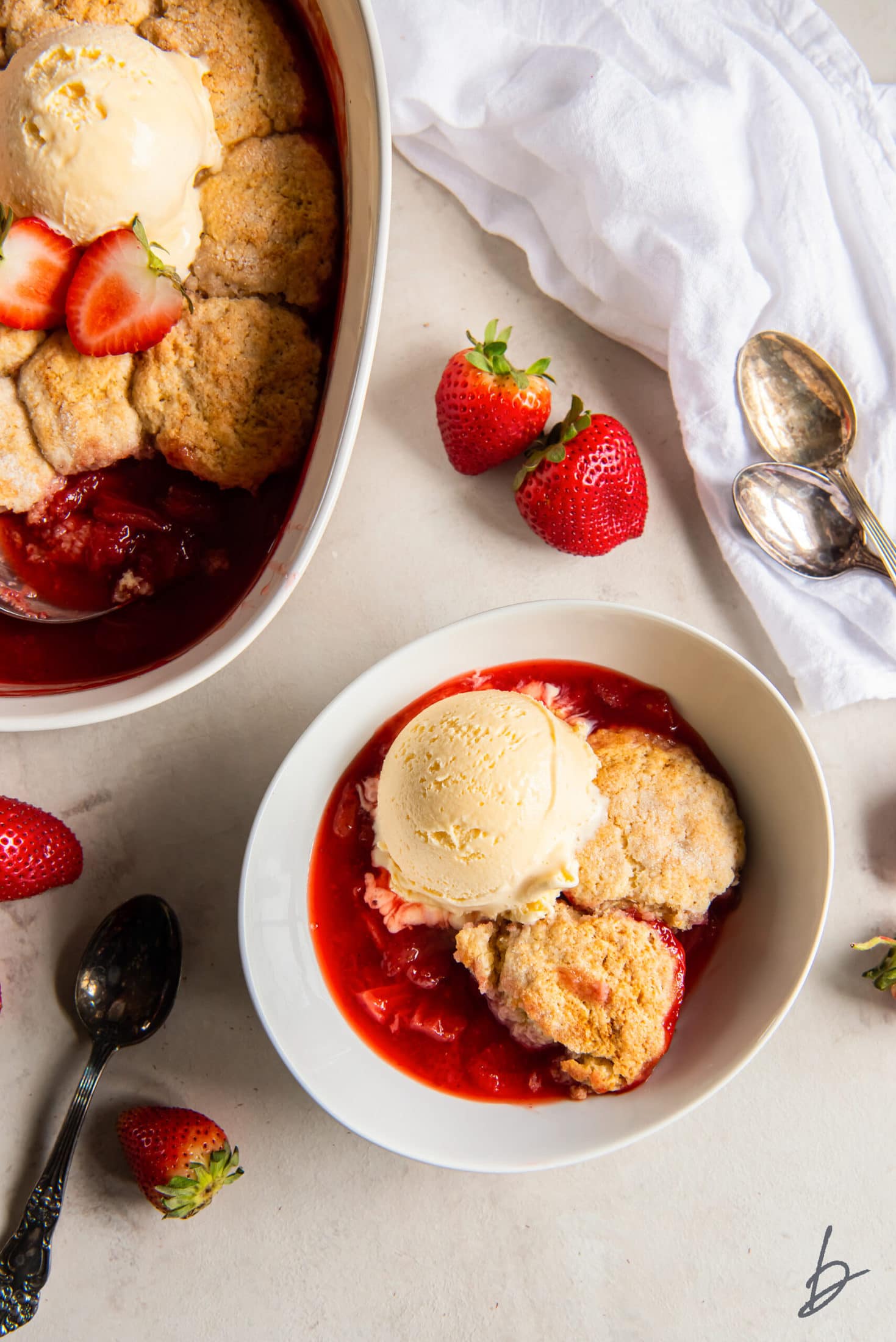 bowl of strawberry cobbler topped with a scoop of vanilla ice cream in a bowl