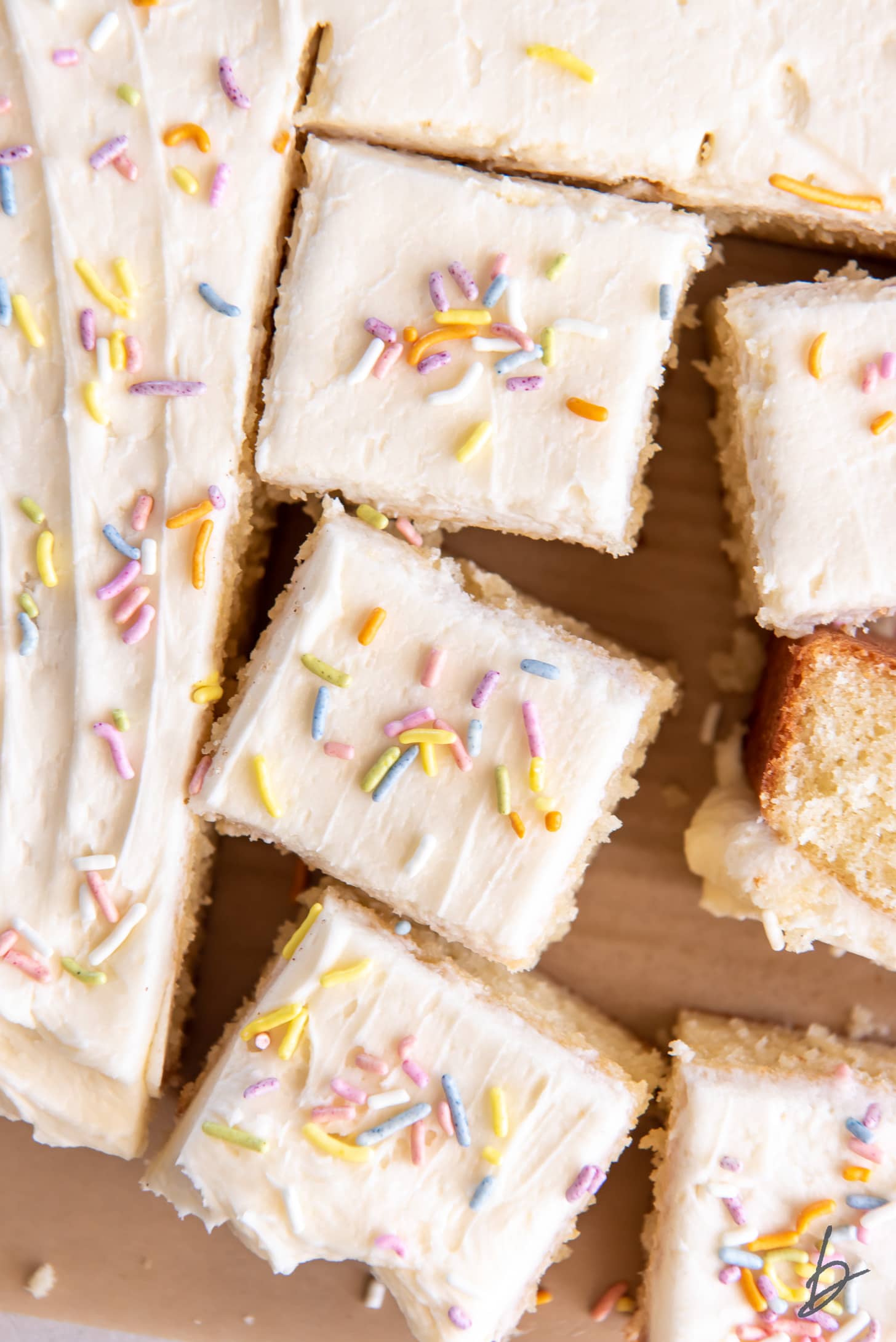 vanilla buttercream frosting and sprinkles on top of square vanilla sheet cake slices