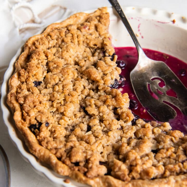 pie server in plate of blueberry crumble pie