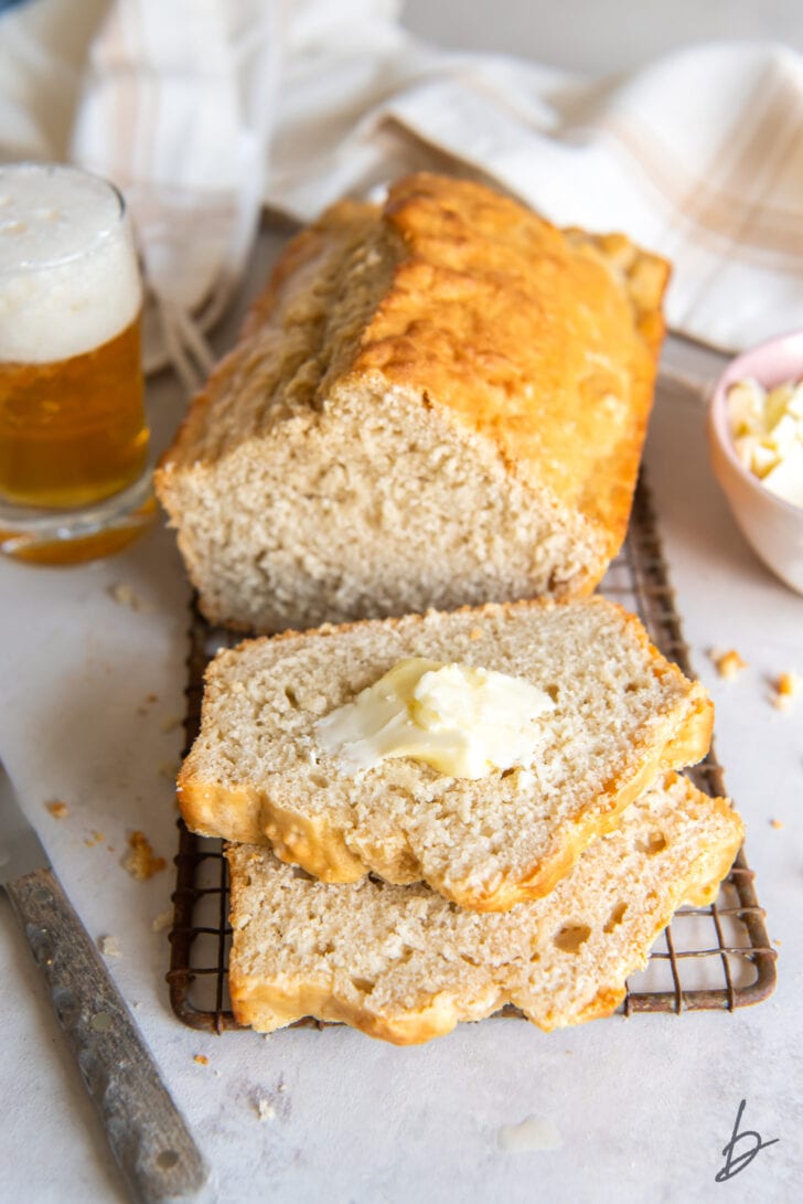 two slices of beer bread cut off loaf with pad of melted butter on top slice