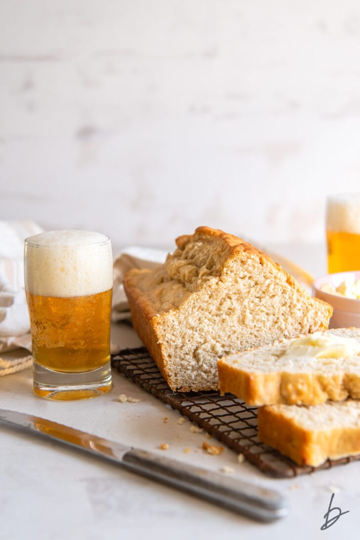pint glass of beer with foam next to loaf of beer bread with end cut off
