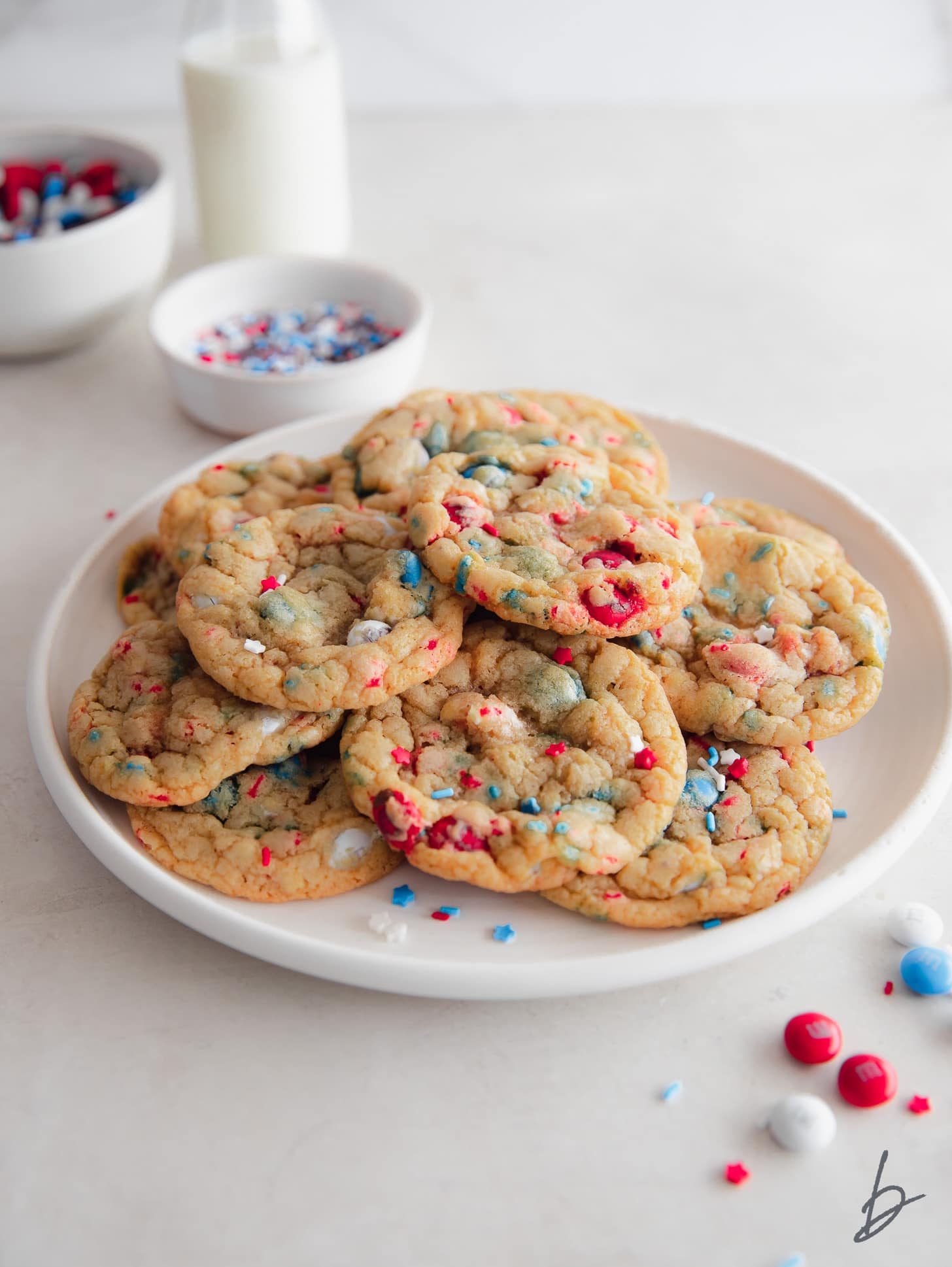 4th of july cookies on a plate next to red, white and blue m&ms and sprinkles