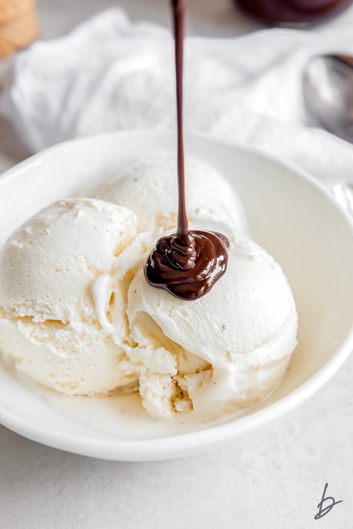 hot fudge sauce drizzled on vanilla ice cream in a white bowl