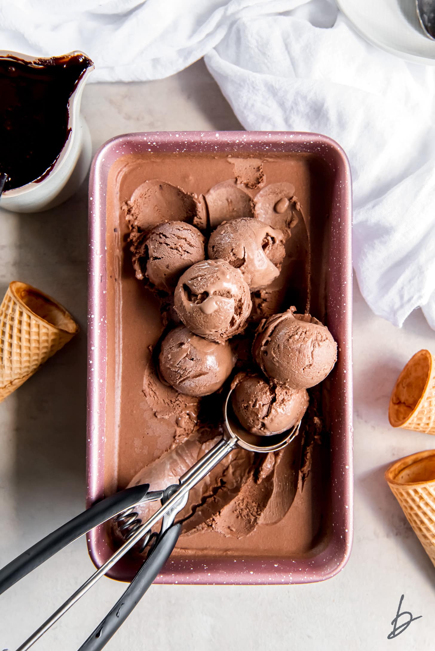 9x5 loaf pan filling with chocolate ice cream and ice cream scoop holding a scoop of ice cream