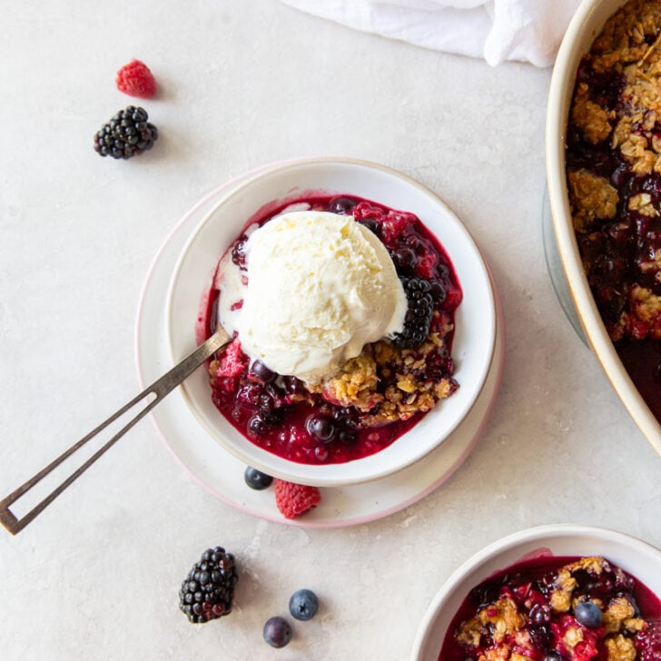 bowl of triple berry crisp with scoop of vanilla ice cream on top melting