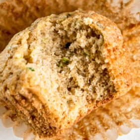 zucchini bread muffin with a bite on paper liner