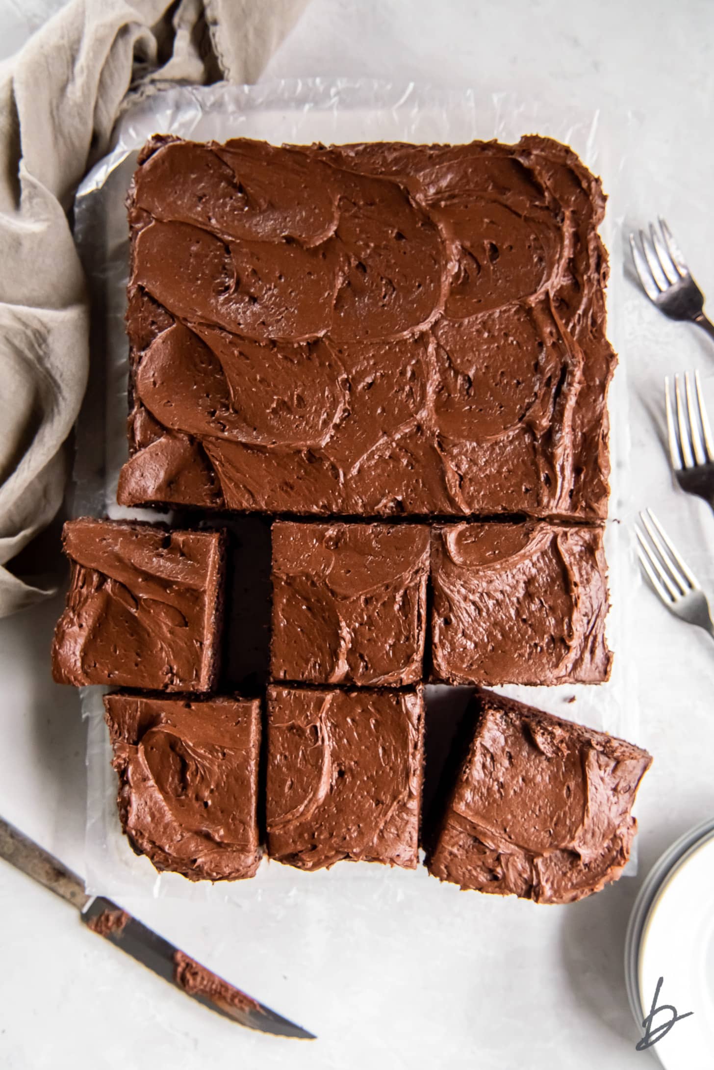 chocolate zucchini sheet cake with chocolate frosting and half the cake cut into squares