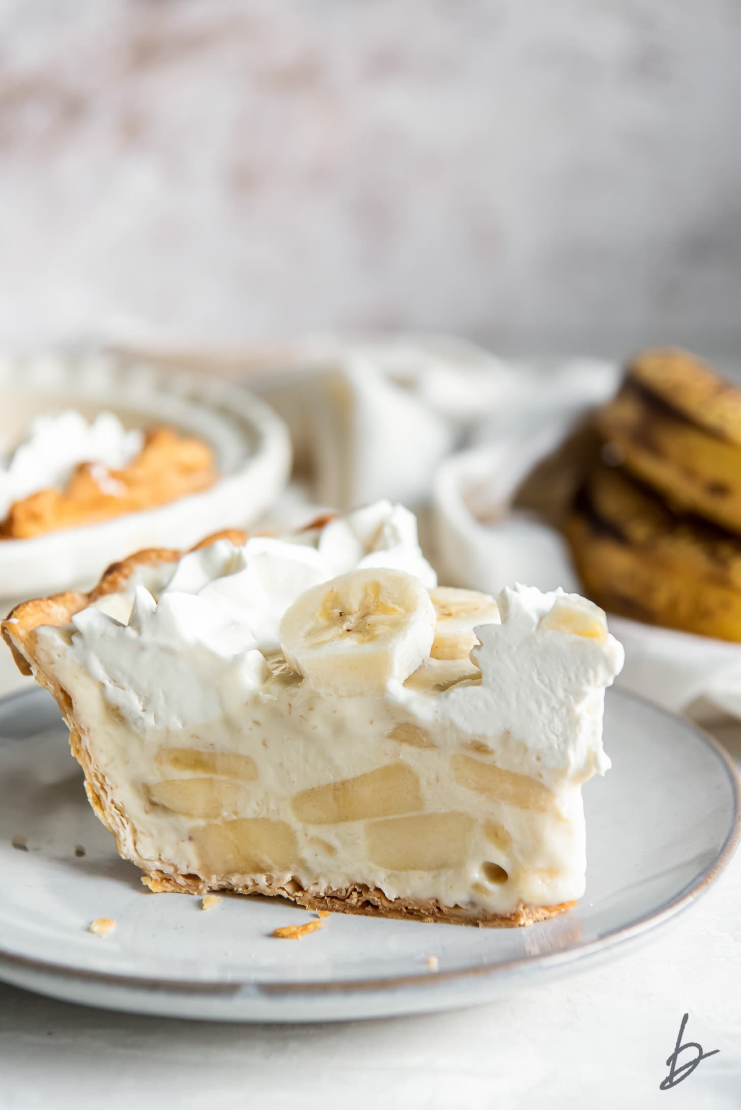 slice of banana cream pie with side showing banana slices inside custard filling