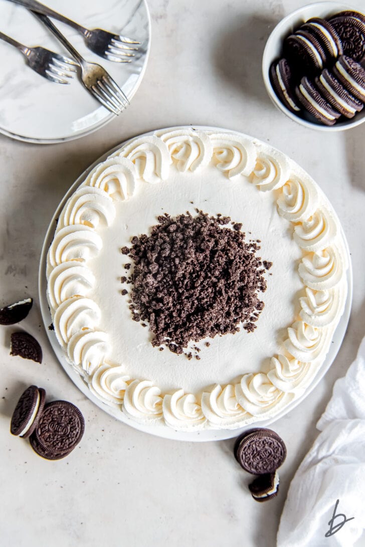top of an ice cream cake with whipped cream piped on the edges and cookie crumbs in the center