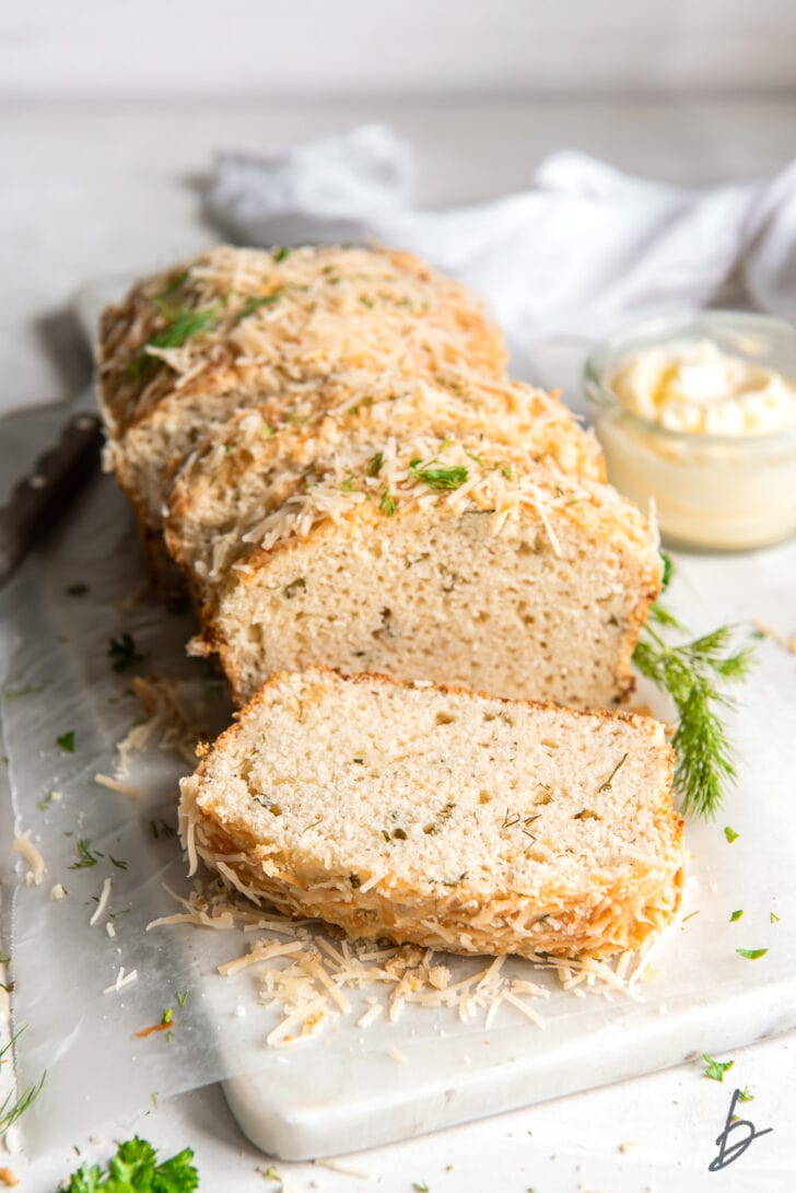 loaf of parmesan herb quick bread with end cut of on marble slab