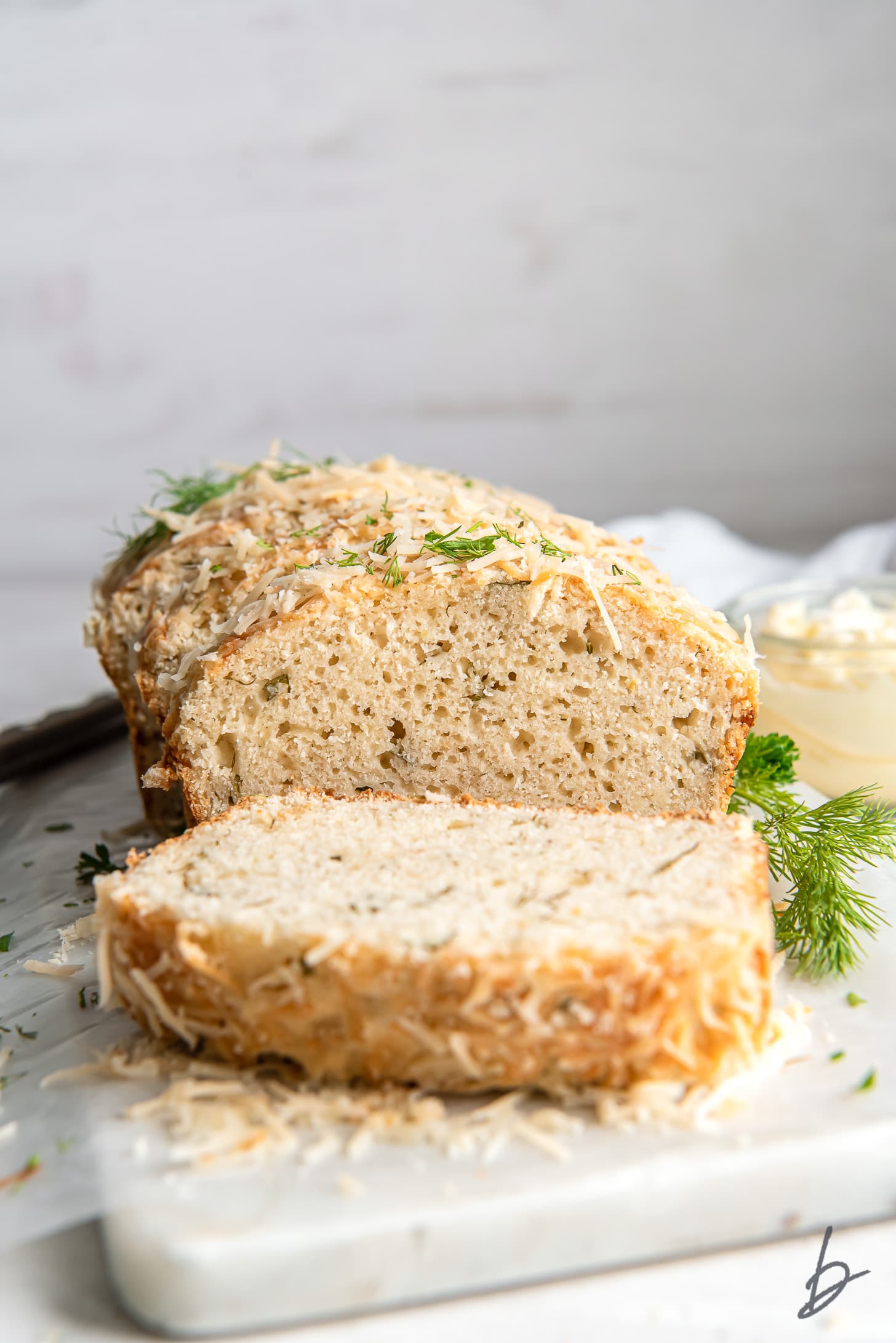 end slice of parmesan herb quick bread on its side in front of loaf