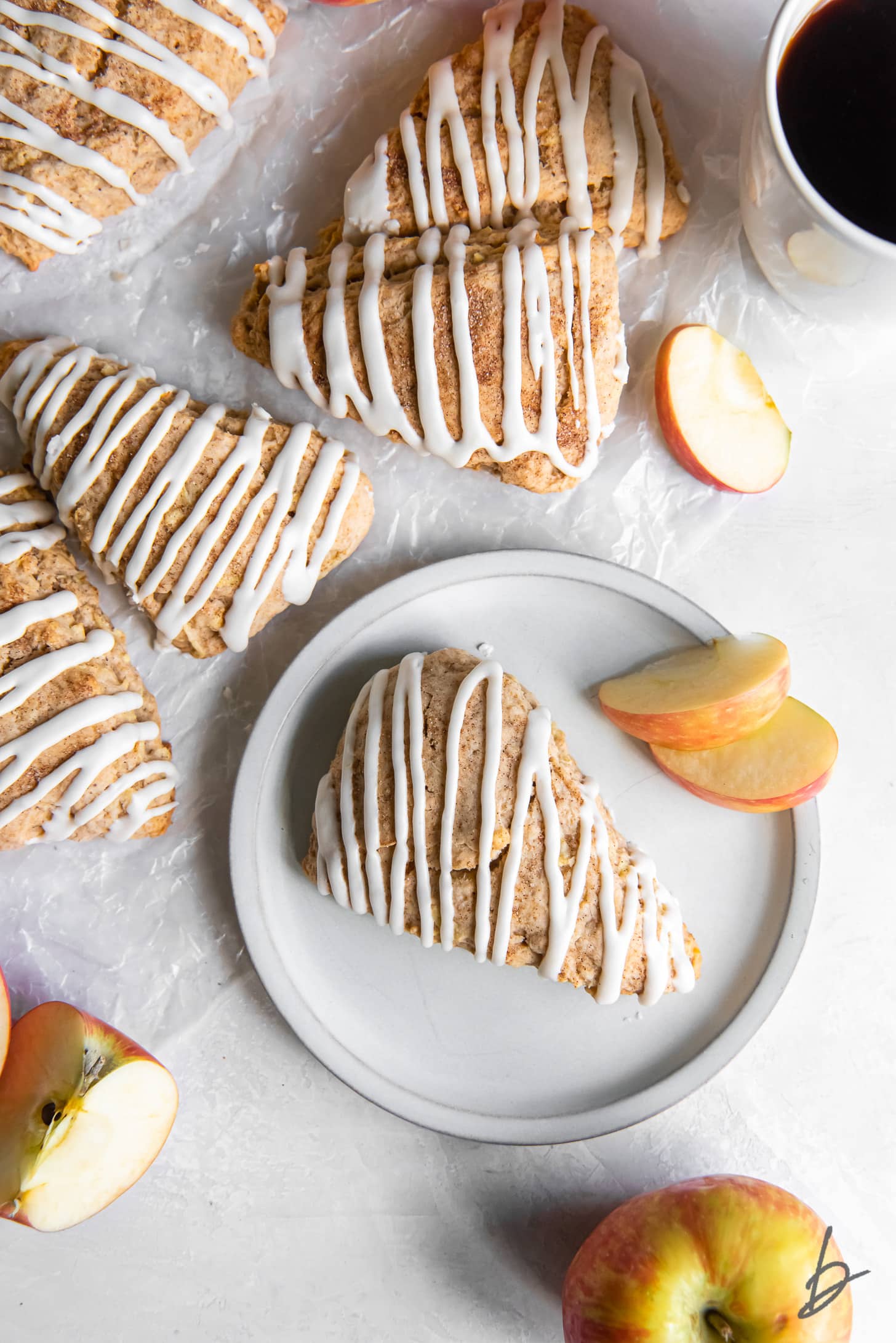 glazed apple cinnamon scone on a plate next to more scones.