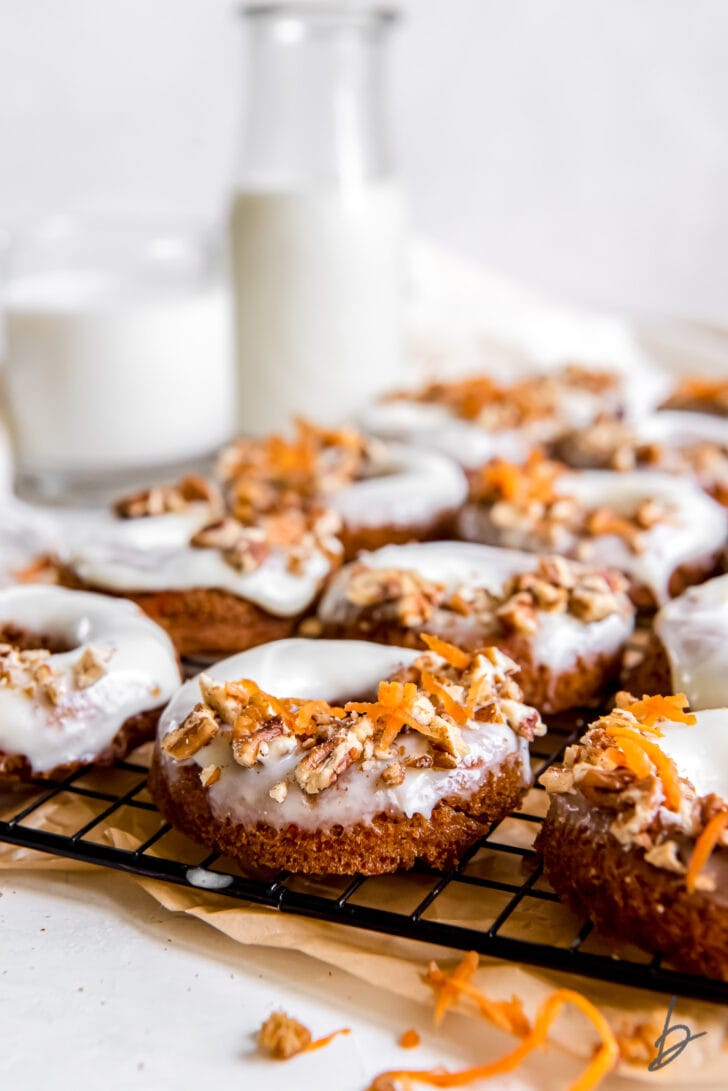 chopped nuts and shredded carrots on frosted carrot cake donut