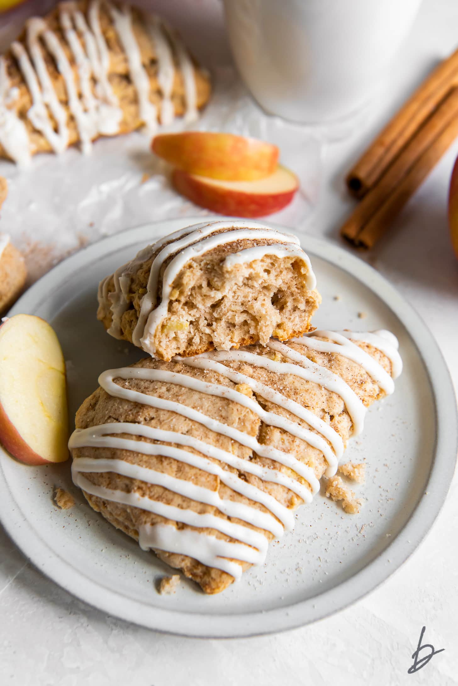 apple cinnamon scone with a bite leaning on another scones with glaze.