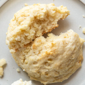 buttermilk biscuit broken in half on white plate.