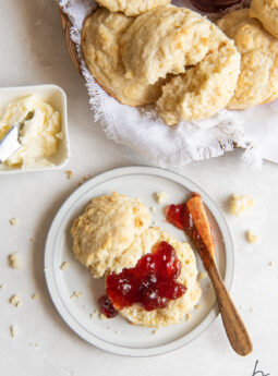jam spread on buttermilk biscuit half on plate with knife