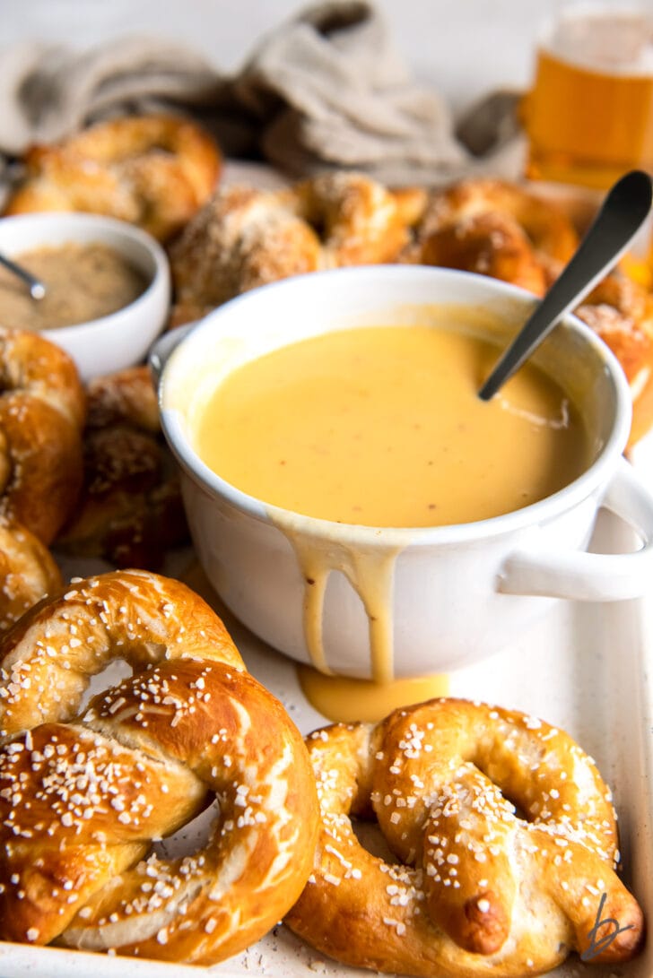 bowl of beer cheese dip with spoon next to soft pretzels