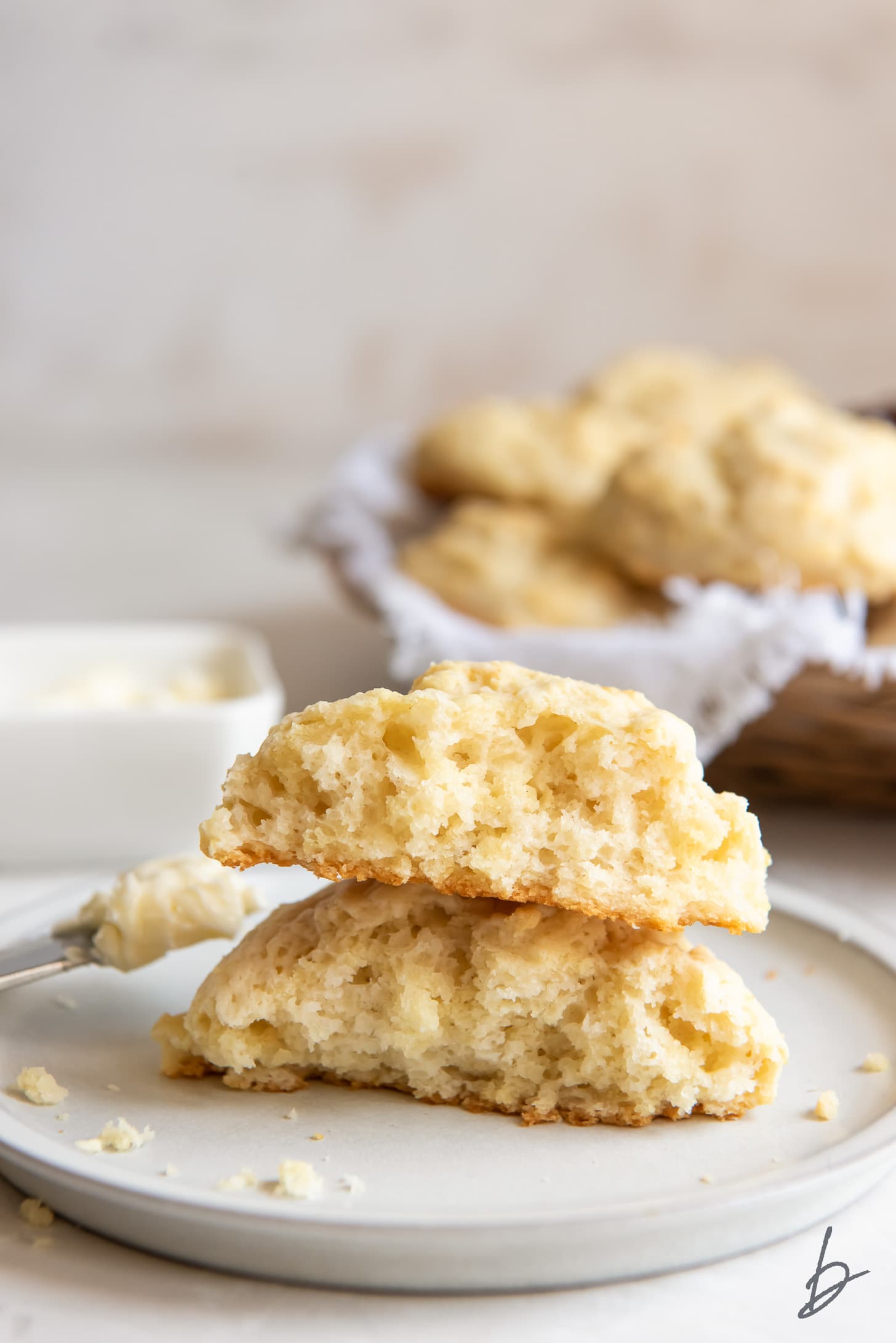 two halves of buttermilk drop biscuit stacked on top of each other on plate.