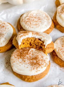 bite taken out of pumpkin cookie with cream cheese frosting.