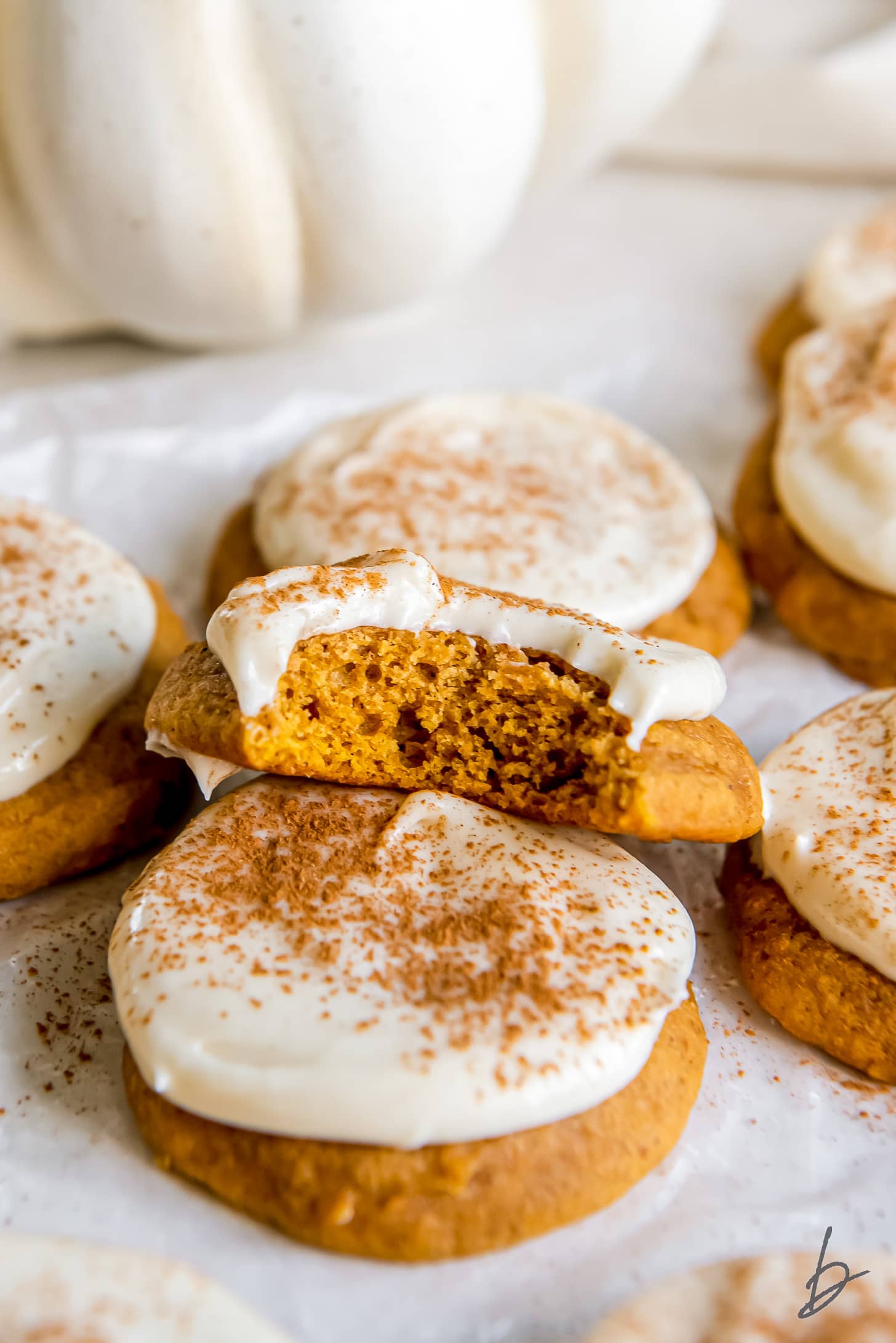 pumpkin cookie with cream cheese frosting with a bite taken.