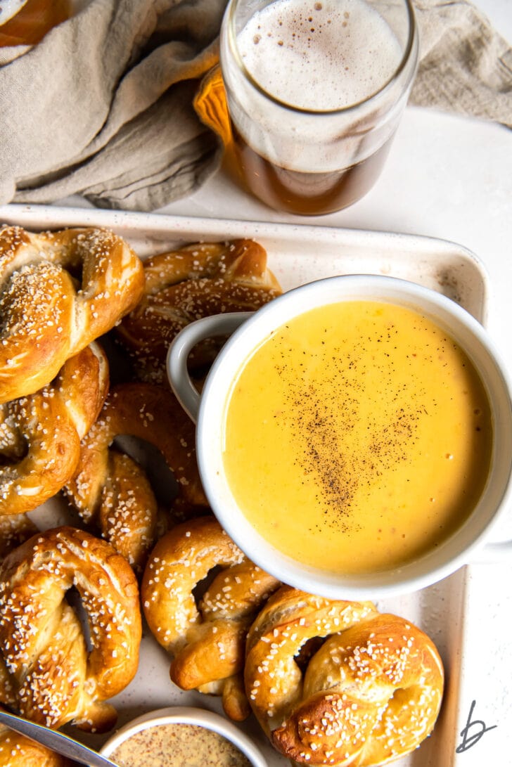 bowl of beer cheese dip on platter with homemade soft pretzels