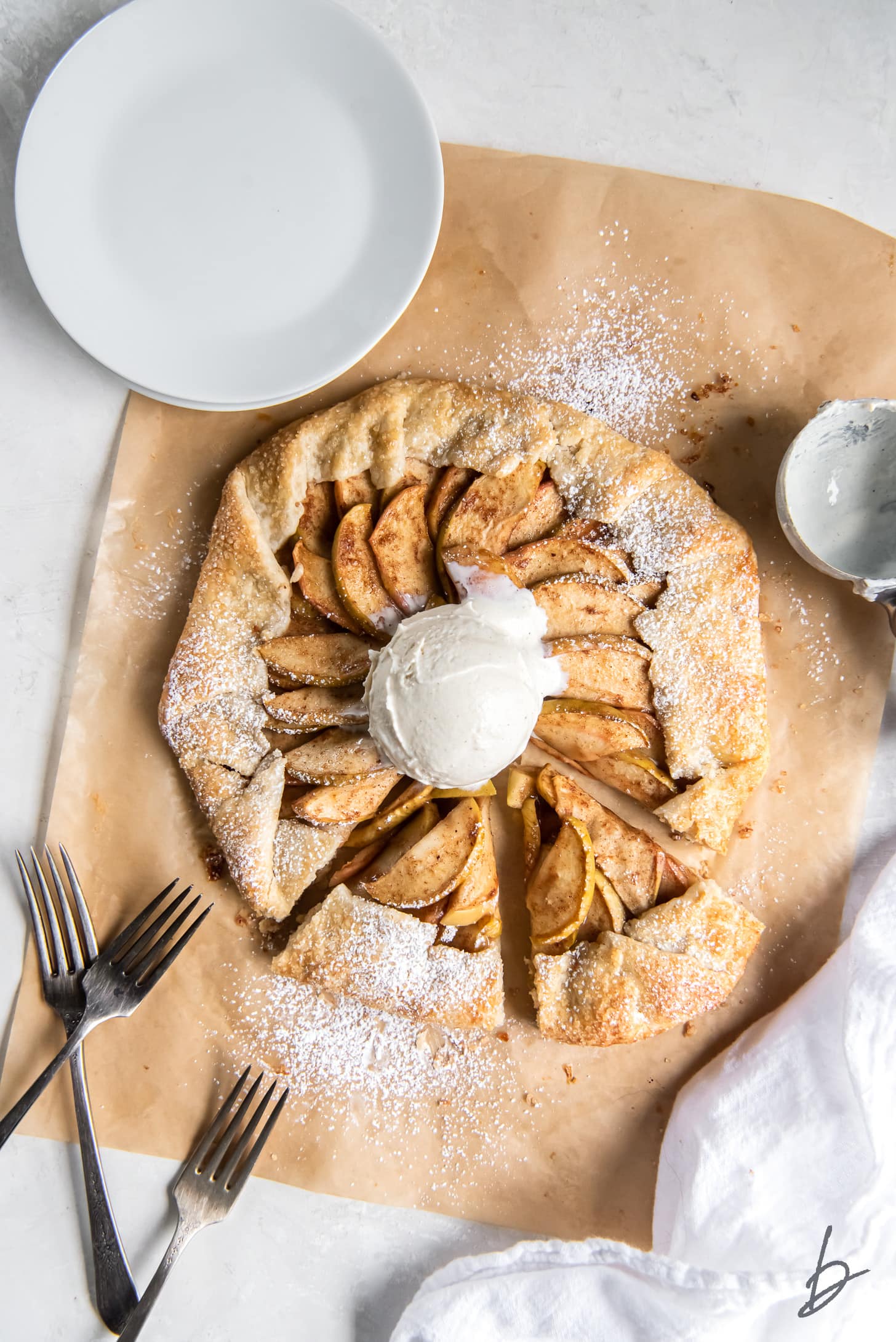 apple galette with scoop of ice cream on parchment paper.