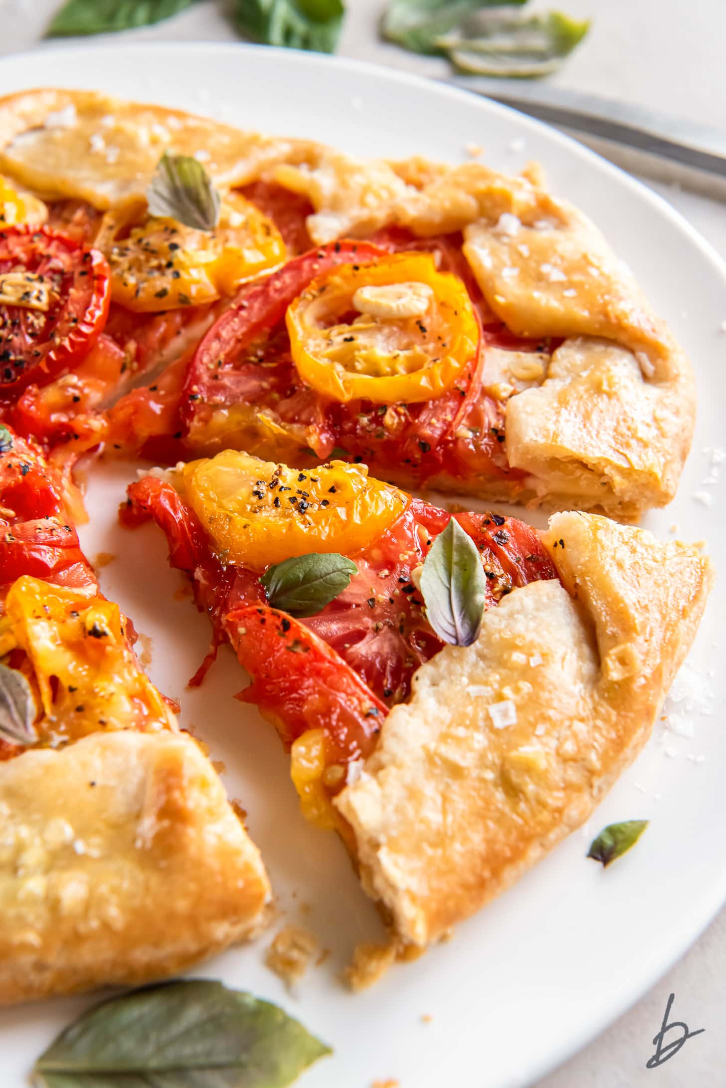 tomato galette with slice cut out and fresh chopped basil on top