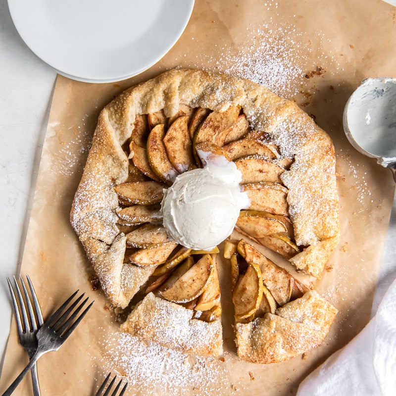 apple galette on parchment paper with ice cream scoop in center.
